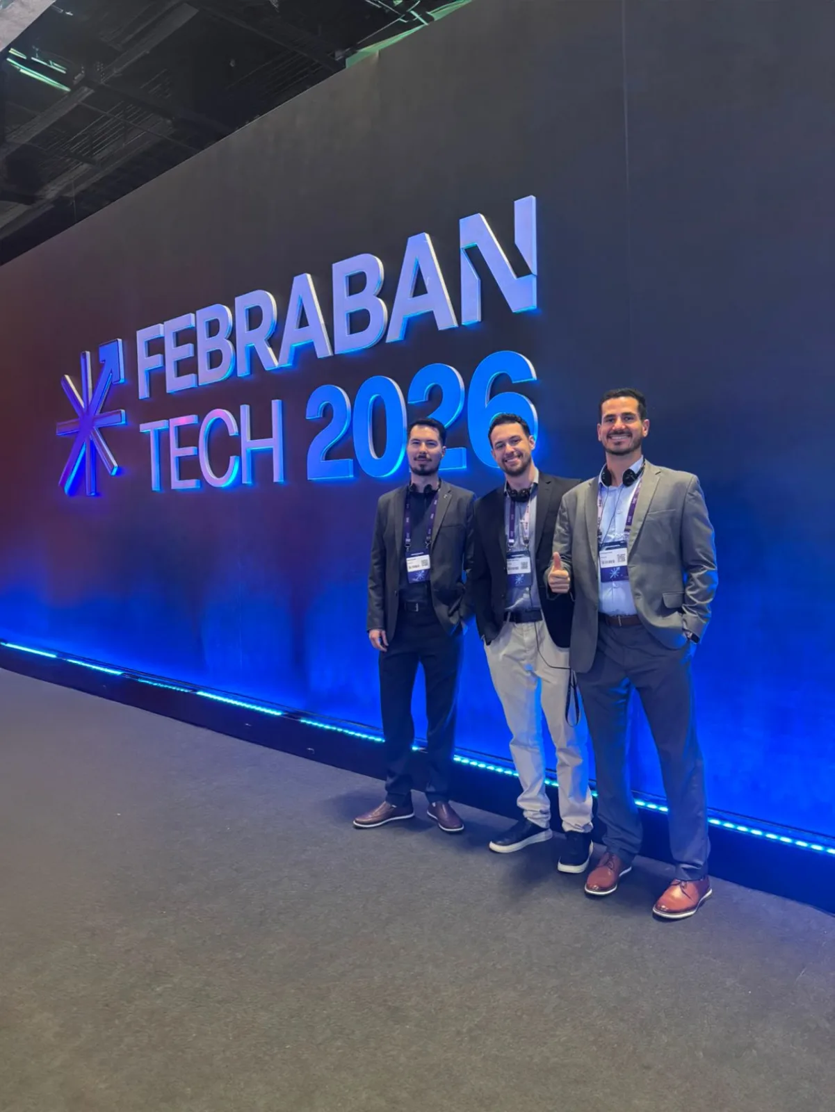 Three team members in front of the illuminated Febraban Tech 2026 wall