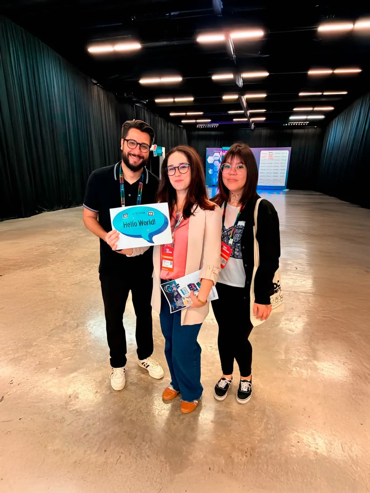 Three team members holding a Hello World sign at The Developer's Conference
